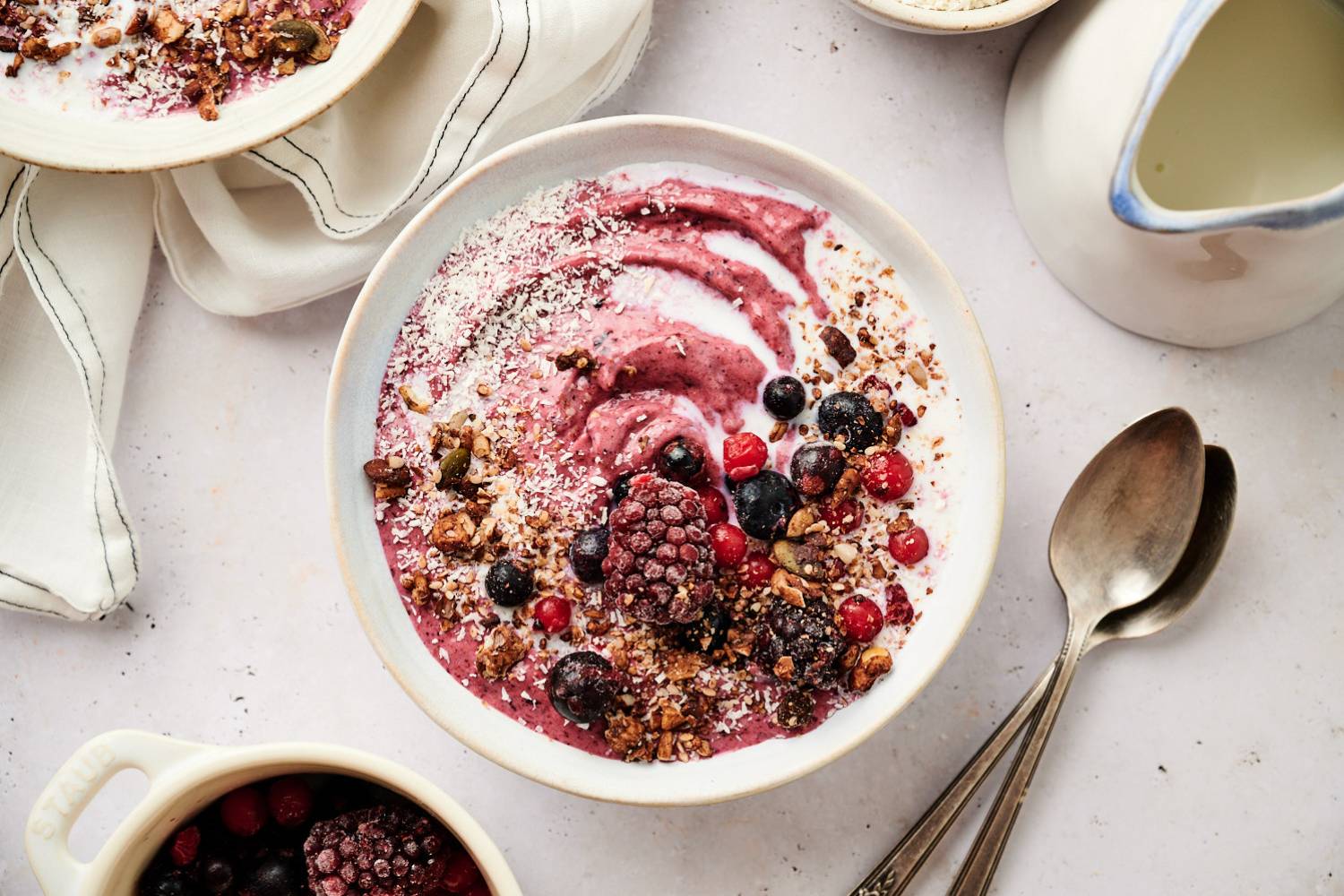 Acai bowl topped with frozen berries, granola, shredded coconut, and a swirl of yogurt.