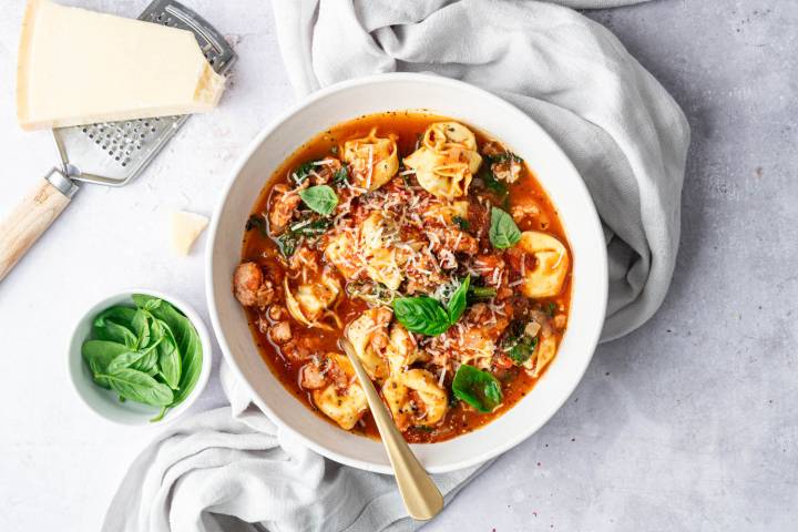 Slow Cooker Tortellini Soup A warm and hearty bowl of Slow Cooker Tortellini Soup filled with tender tortellini, flavorful sausage, spinach, and tomatoes, topped with freshly grated Parmesan and basil for a comforting finish.
